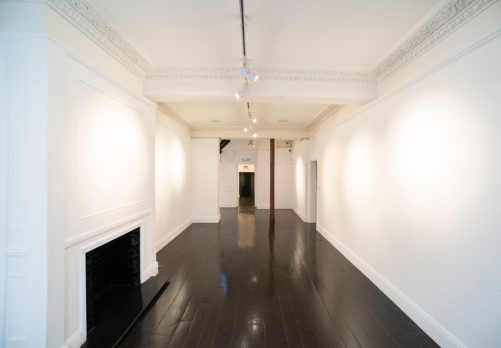 White-walled gallery interior at 15 Bateman Street with dark wood floors and track lighting